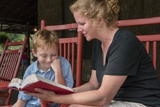 Caucasian mother and son reading on patio
