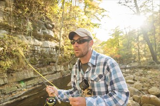 Caucasian man fishing in forest stream