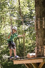 Caucasian boy balancing on slackline in forest