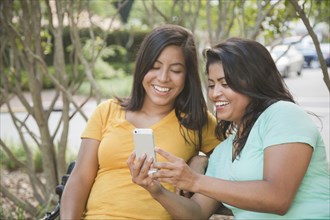 Hispanic mother and daughter posing for cell phone selfie