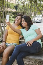 Hispanic mother and daughter posing for cell phone selfie