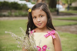 Hispanic girl holding flowers in park