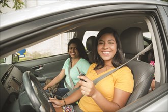 Smiling Hispanic mother and daughter posing in car