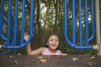 Smiling Hispanic girl reaching on playground