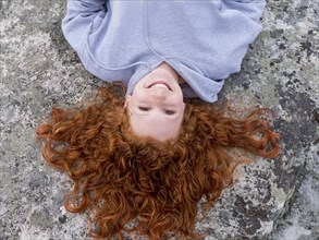 Portrait of smiling Caucasian girl laying on rock