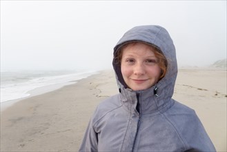 Portrait of smiling Caucasian girl on cold beach