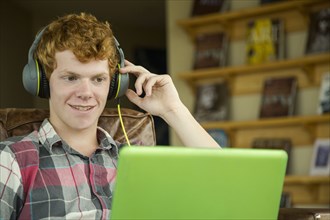 Smiling Caucasian boy listening to laptop with headphones