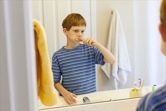 Reflection of Caucasian boy brushing teeth in mirror