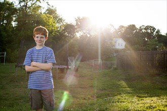 Smiling Caucasian boy standing in sunny backyard