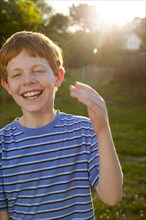 Smiling Caucasian boy laughing in sunny backyard