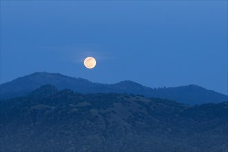 Glowing moon rising over foothills