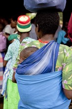 Close up of mother carrying baby with traditional wrap