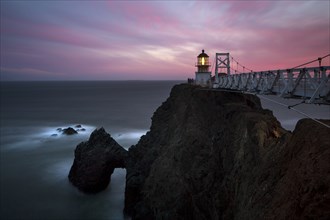 Lighthouse on rocky cliffs over ocean coastline