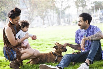 Parents playing with baby son and dog in park