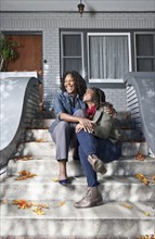 Black mother and daughter sitting on front stoop