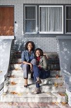 Black mother and daughter sitting on front stoop