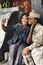 Black mother taking self-portrait with soldier daughter