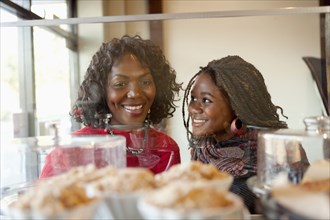 Black mother and daughter looking at pastry in cafe