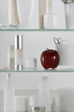 Medicine cabinet full of skincare products and a red apple