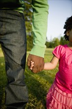 Black father and daughter holding hands in park