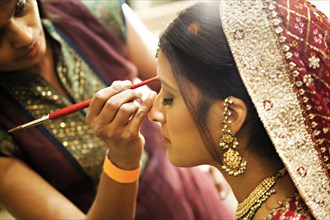 Indian woman in traditional clothing having make up applied