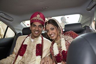 Indian bride and groom in traditional clothing in car