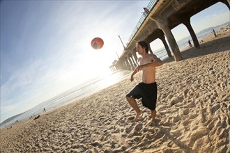 Hispanic man playing with soccer ball on beach