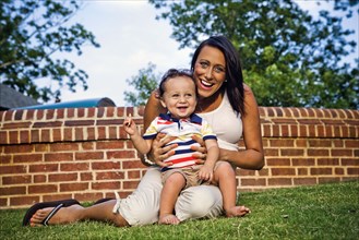 Mixed race mother and son sitting in grass
