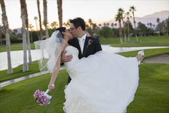 Newlywed couple kissing on golf course