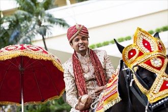 Indian groom riding horse in wedding procession