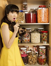 Mixed race woman taking lollipop from cupboard