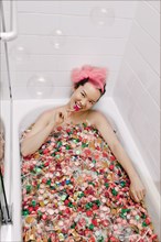 Mixed race woman taking a bath in candy