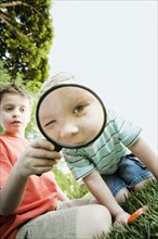 Caucasian brothers looking through magnifying glass
