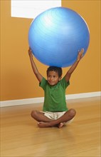 Mixed race boy lifting exercise ball