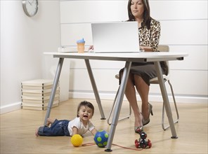 Hispanic working mother and baby son in home office