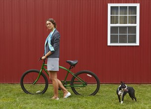 Mixed race businesswoman standing with bicycle and dog