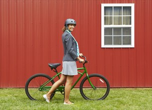 Mixed race woman in helmet standing with bicycle