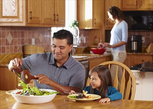 Father serving daughter salad