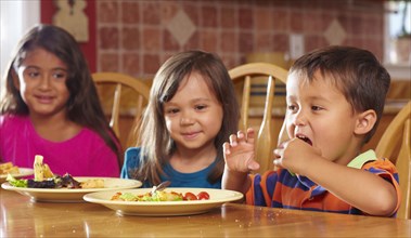 Children eating dinner at table together