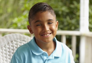 Smiling Hispanic boy sitting on porch