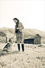 Woman petting dog in rural landscape