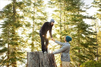 Couple playing on tree stump in forest