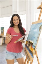 Portrait of smiling woman painting at easel