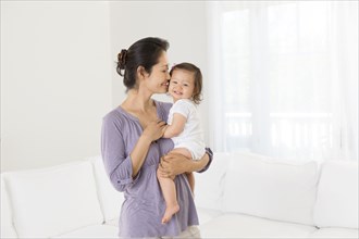Mother holding baby girl in living room