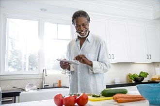 Senior man using digital tablet in kitchen
