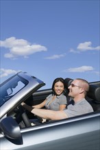 Multi-ethnic couple driving in convertible car