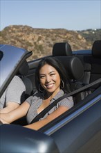 Asian woman driving convertible car