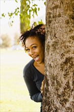 Playful African woman behind tree