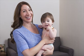 Mixed race mother holding baby daughter in living room