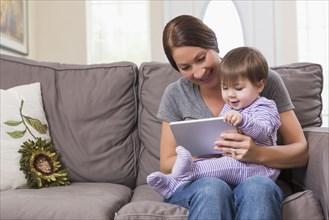 Mixed race mother and baby daughter using digital tablet